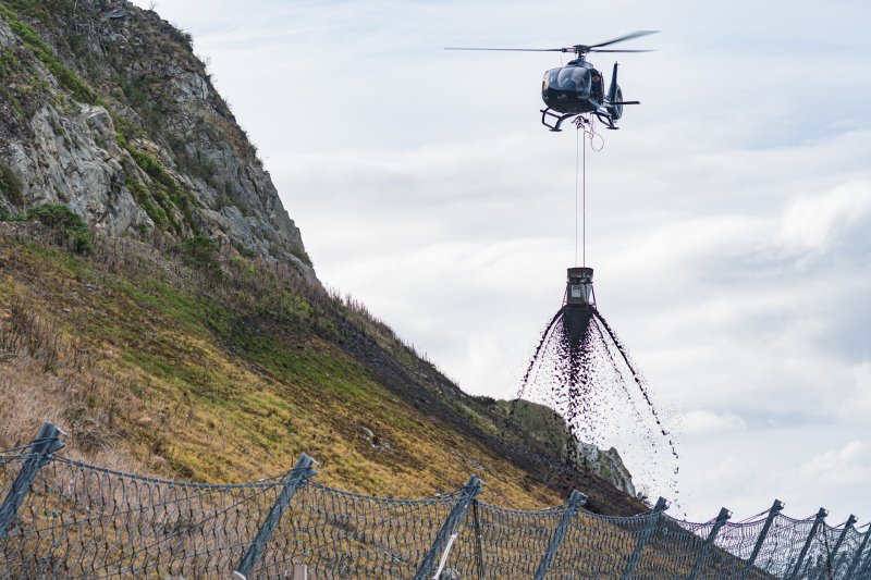 A helicopter dropping chemicals onto a mountain side