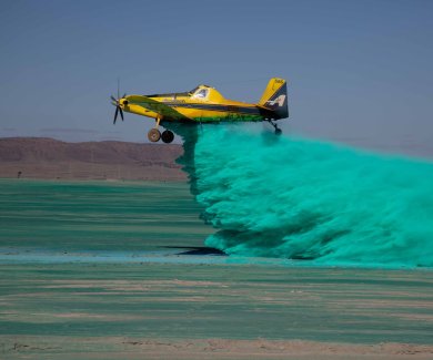 A plane spraying dust suppression chemicals over a field.